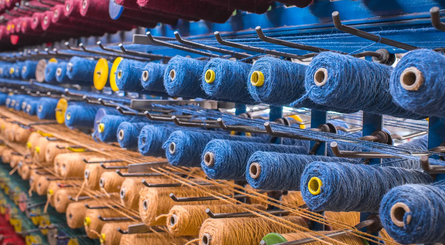 Hero image of yellow, blue and red British wool being used to make carpets