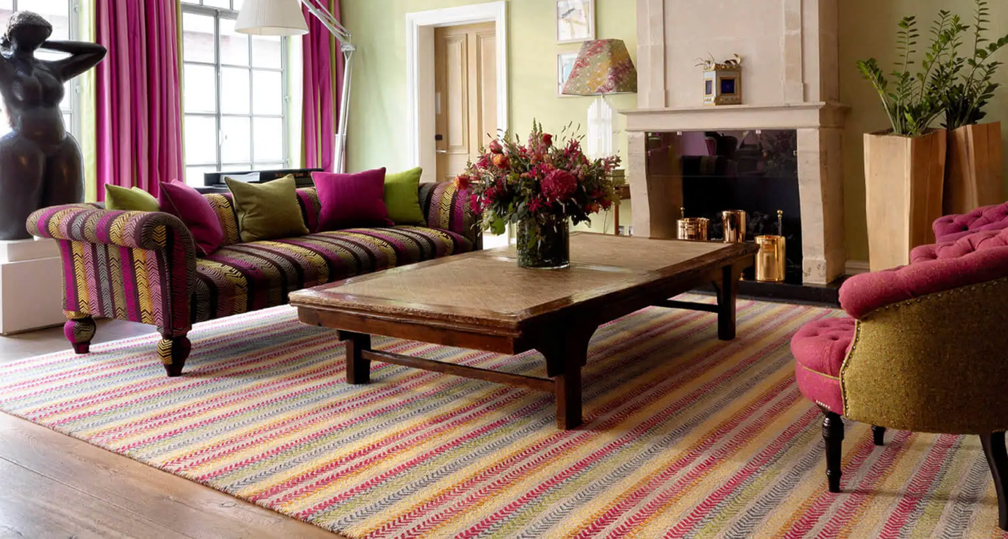 Hero image of a sitting area, with a multicoloured rug to match the interior of the room