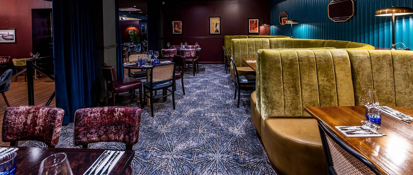 A cosy restaurant with blue patterned carpets and hexagonal white shapes